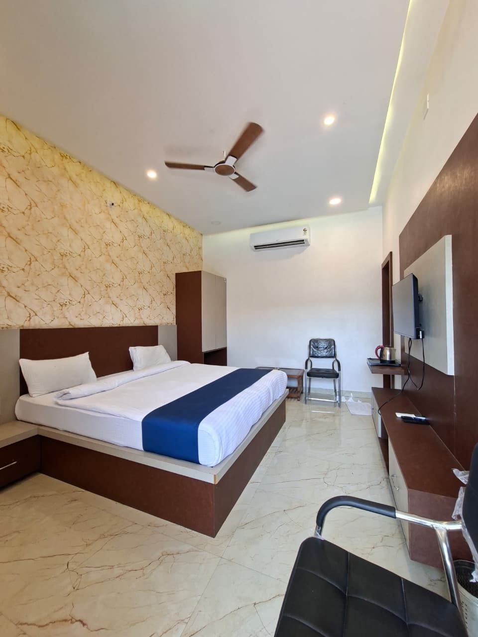 Deluxe room at The Ambay Villa Udaipur with wall-mounted TV and luggage chair